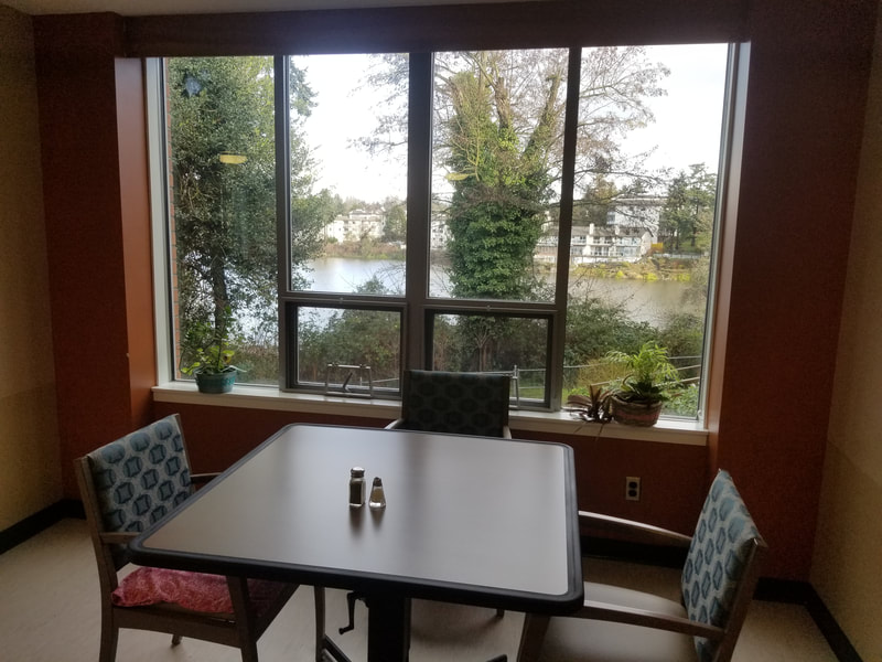 Dining room with tables and chairs positioned by large windows overlooking greenery and the Gorge waterway.