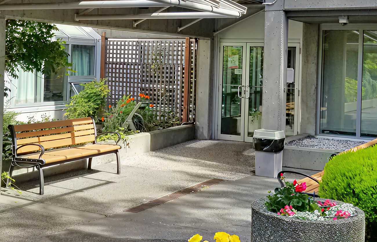 Building entrance with outdoor seating, planters, and landscaped grounds welcoming visitors.