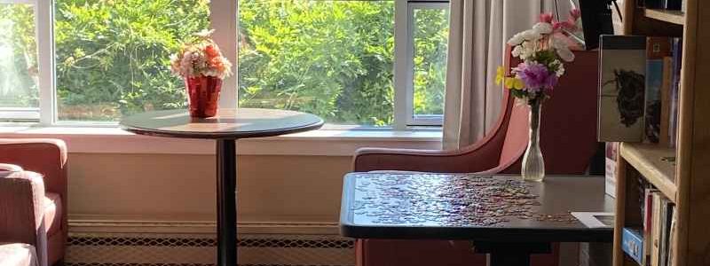 Small seating alcove with a table and chairs beside a window, designed as a quiet space for residents.